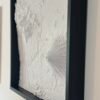 Angled close-up of a framed white terrain map showing a volcanic cone and fine relief detail