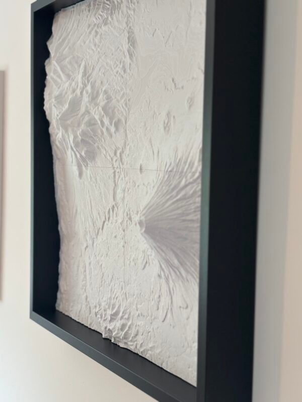 Angled close-up of a framed white terrain map showing a volcanic cone and fine relief detail