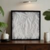 White 50 × 50 cm 3D terrain map in a black frame displayed on a wooden sideboard