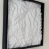 Angled view of a white four-tile terrain map mounted in a deep black frame