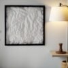 Framed white 3D topographic map hanging on a wall beside a lamp